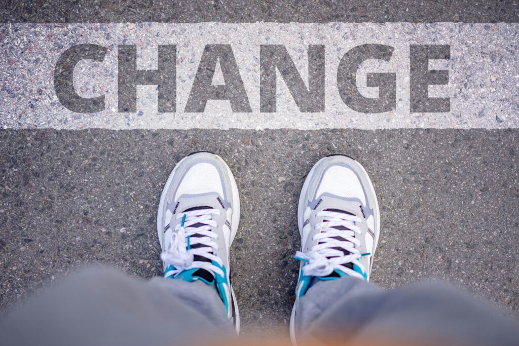 Close-up of sneakers on street with 'Change' text, symbolizing transformation.
